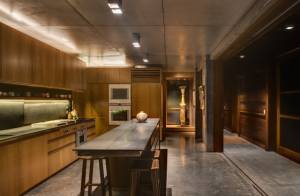 Black-granite-countertops-wooden-kitchen-cabinet-wooden-bar-stool-concrete-floor-spotlight-wooden-wall-artwork